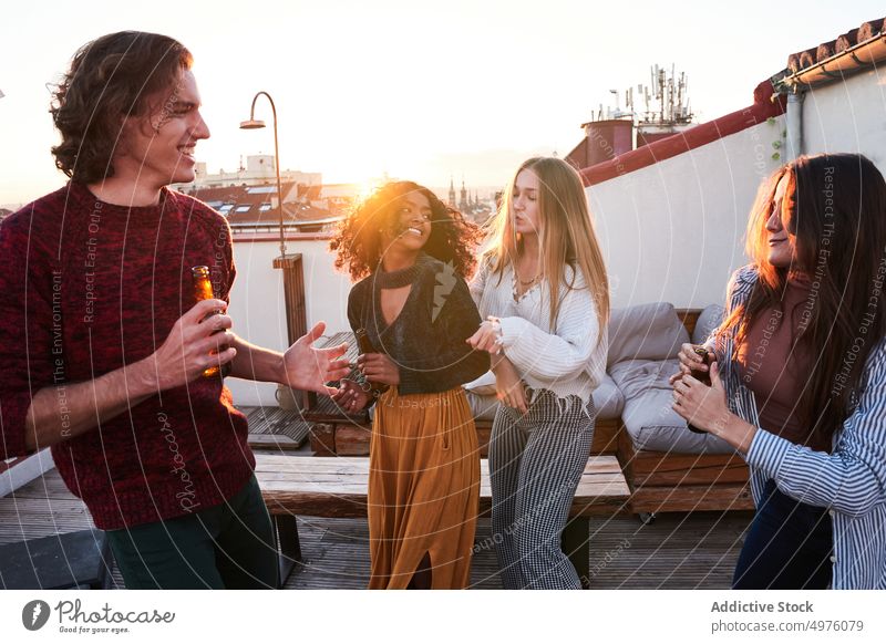 Joyful diverse friends dancing and enjoying beer on rooftop dance party booze happy together sunset hangout active beverage celebrate fun friendship having fun