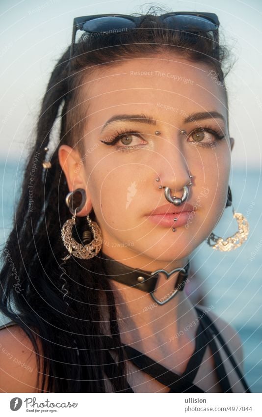 portrait of sensitive young teenager woman, girl with dark hair, dreadlocks, many piercings face summer sunset creative gothic hippie mischievous sensuality