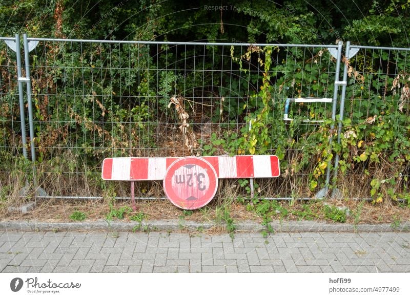 red sprayed warning sign about clearance height on barge in front of construction fence and bushes. - urban still life height limit Road sign vertical clearance