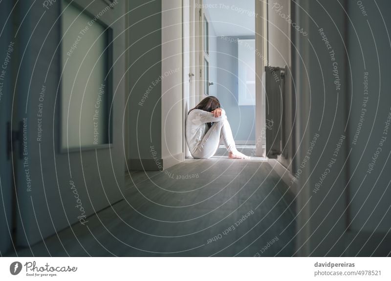 Woman in pajamas sitting on the floor of a mental health center unrecognizable woman disorder problems hospital patient psychiatric corridor head leaning arms