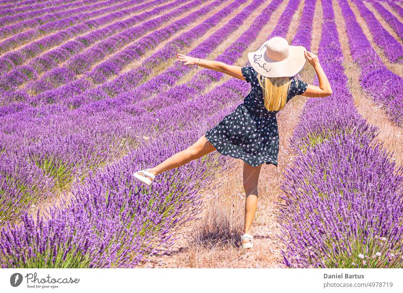 Close up of a young girl in a floral dress with a hat on her head between lavender in southern Provence Valensole France beautiful beauty brunette caucasian