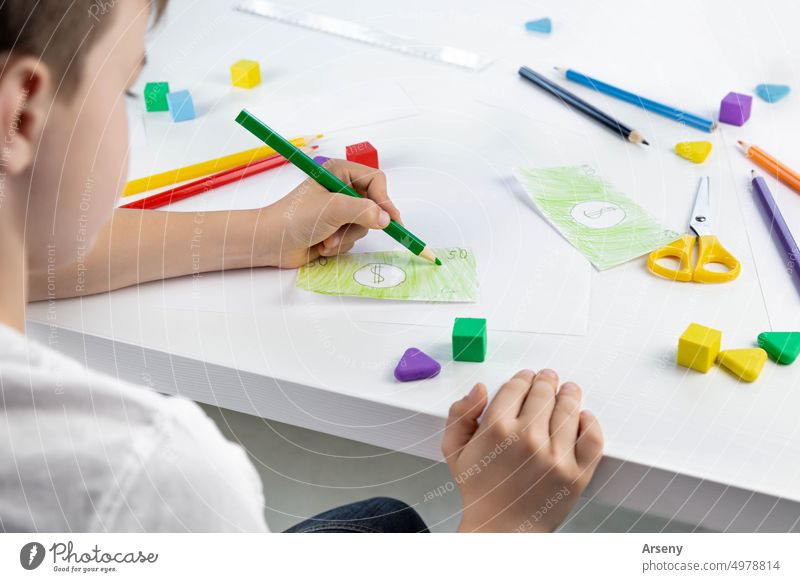 A little boy enthusiastically draws toy money with colored pencils for the game. Selective focus. Family budget play person child childhood cash close up colour