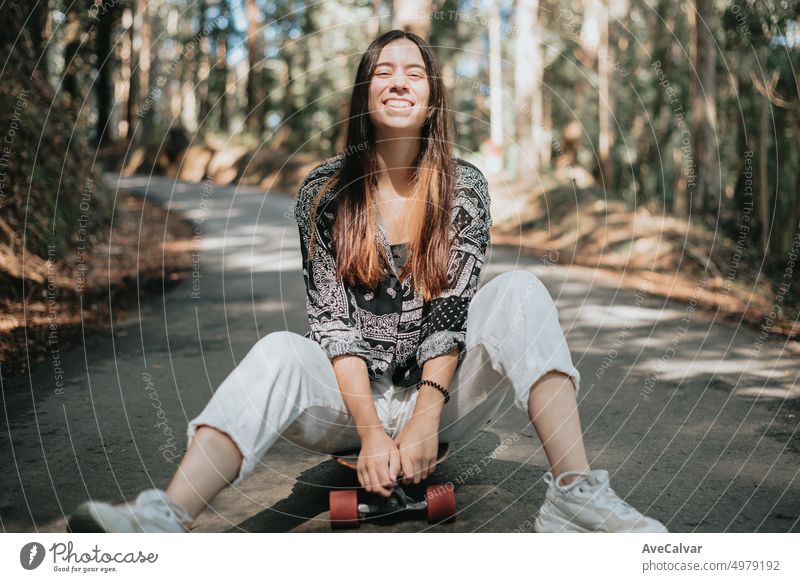 Portrait of young adult woman having fun resting on longboard skate. Learning new skills and sports.Teaching and sharing on social media.New generations and freedom concept