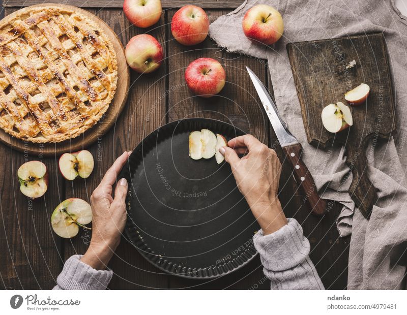 A woman puts apple slices in a round baking sheet on the table, next to the ingredients hand crust sweet nutrition pie rustic food fresh fruit tart thanksgiving