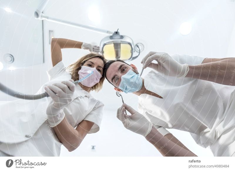 Low angle portrait of male and female dentists wearing masks at dental clinic Dentist dentistry man woman low angle specialist assistant orthodontist
