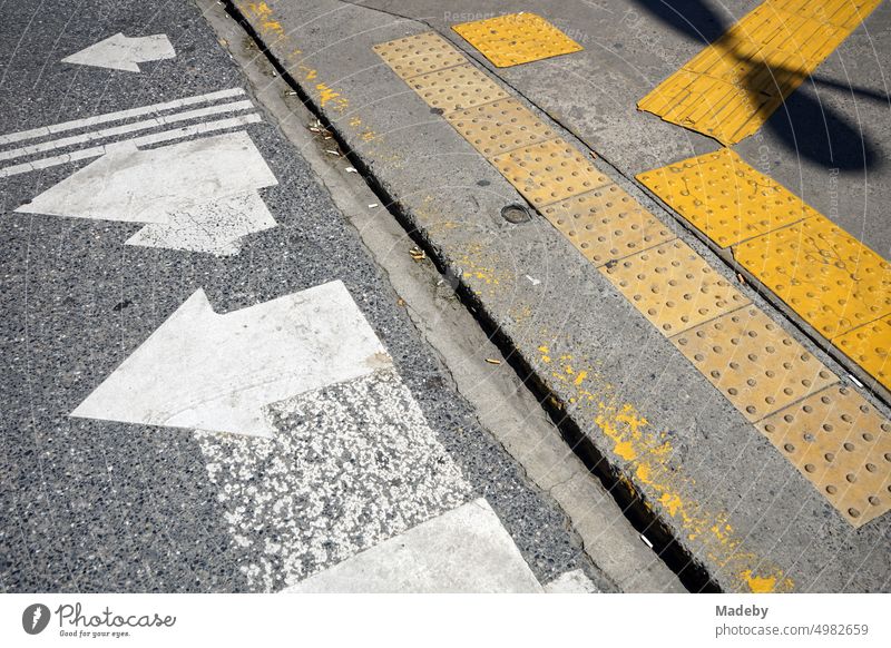Crosswalk with road marking in white and tactile guidance system in yellow on gray asphalt in summer sunshine in the Erenköy district of Istanbul on the Bosporus in Turkey