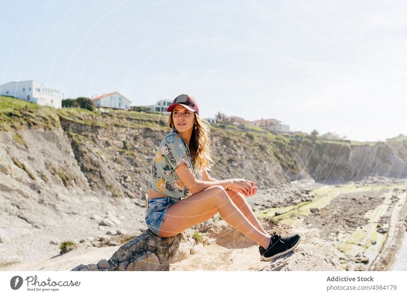 Woman resting on top of a rock by the sea woman sitting sunny beach journey trip transportation vacation adventure travel summer recreation leisure holiday