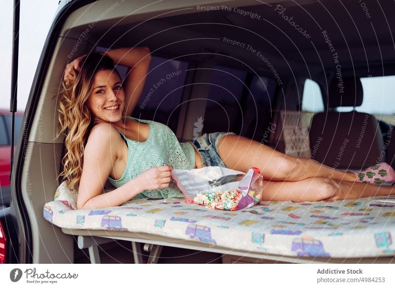 Blonde pretty woman resting in a caravan popcorn trip people travel summer happy lying road smiling young sun transportation teenage caucasian vacation