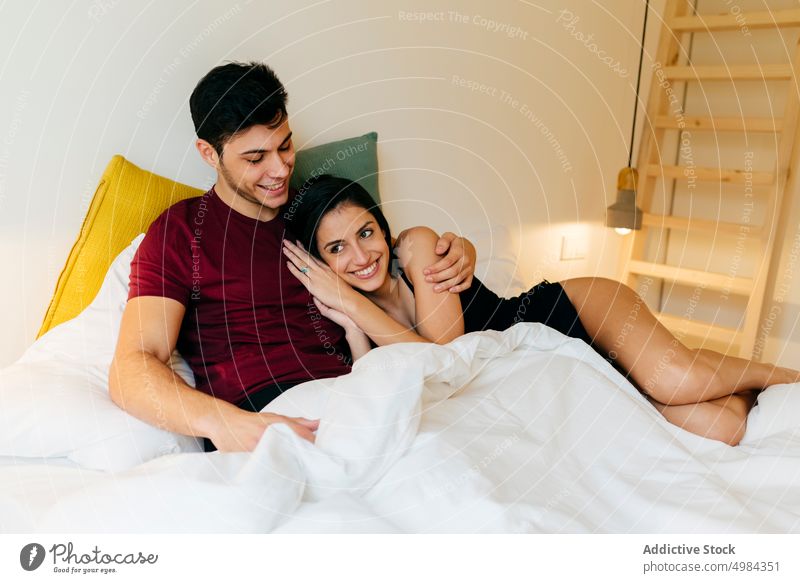 Couple cuddling on bed couple hugging woman linen room volume reading bedroom young white lying blanket embracing together love male female romantic