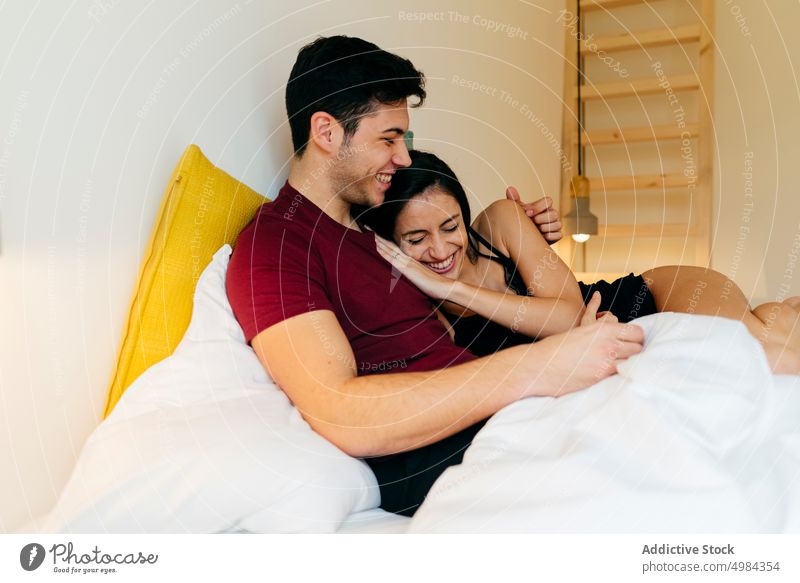 Couple cuddling on bed couple hugging woman linen room volume reading bedroom young white lying blanket embracing together love male female romantic