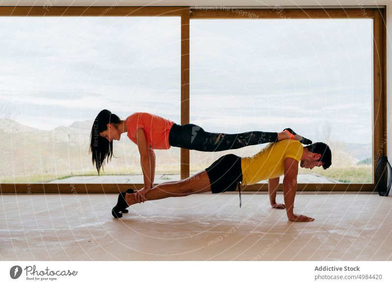 Slim lady and guy standing in plank in room sport sportswear woman athletic slim active window activity gymnastic panorama mountain view countryside leisure