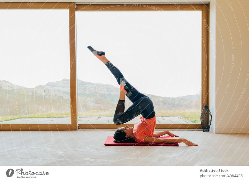 Slim lady sitting stretching in room sport upped hand sportswear woman slim active yoga window activity gymnastic panorama mountain view countryside leisure