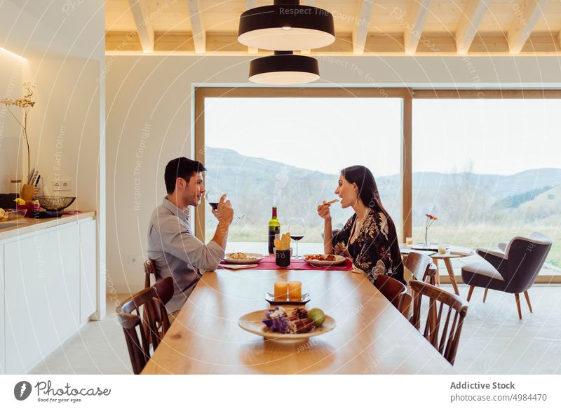 Happy couple dinning at table in kitchen happy hispanic eating plate glass wine smiling woman young attractive cheerful beverage dinner drink meal appetizing