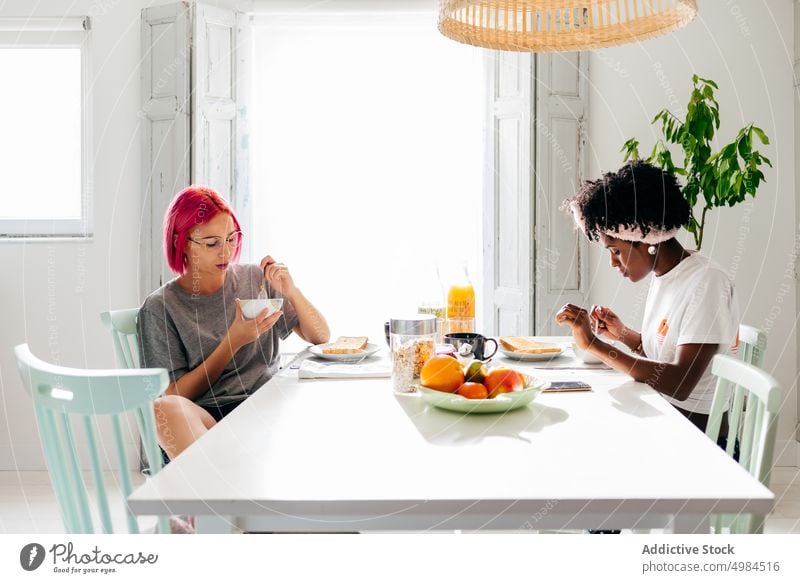 Multiethnic friends having breakfast together women morning home cereal eat diverse happy female table sit healthy dish food tasty young delicious yummy