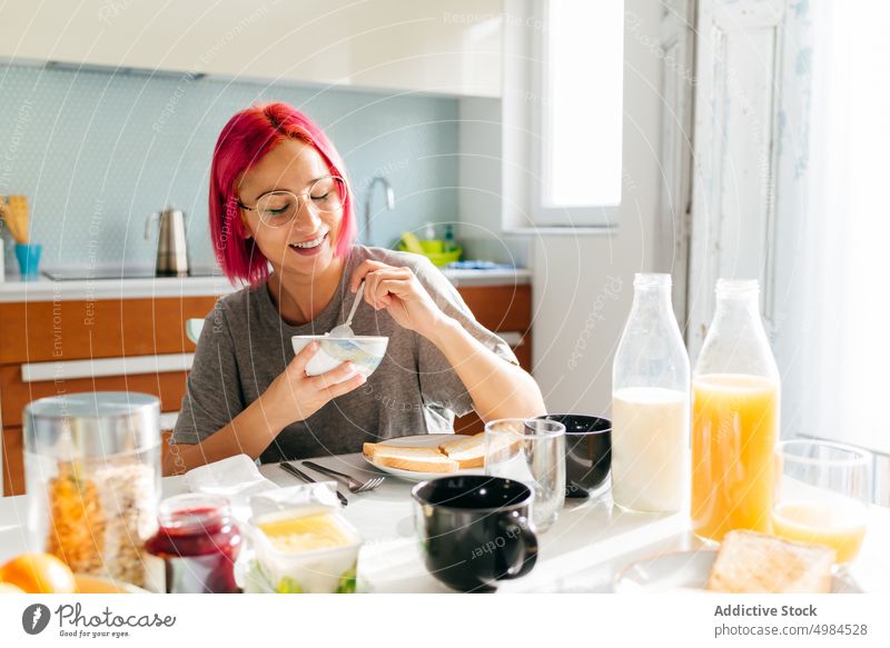 Young lady having healthy breakfast at home woman morning smile table cozy eat kitchen apartment modern female young dyed hair alternative lifestyle food