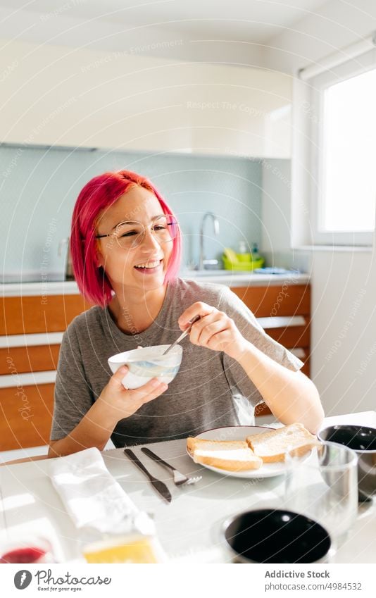 Young lady having healthy breakfast at home woman morning smile table cozy eat kitchen apartment modern female young pink hair dyed hair alternative lifestyle