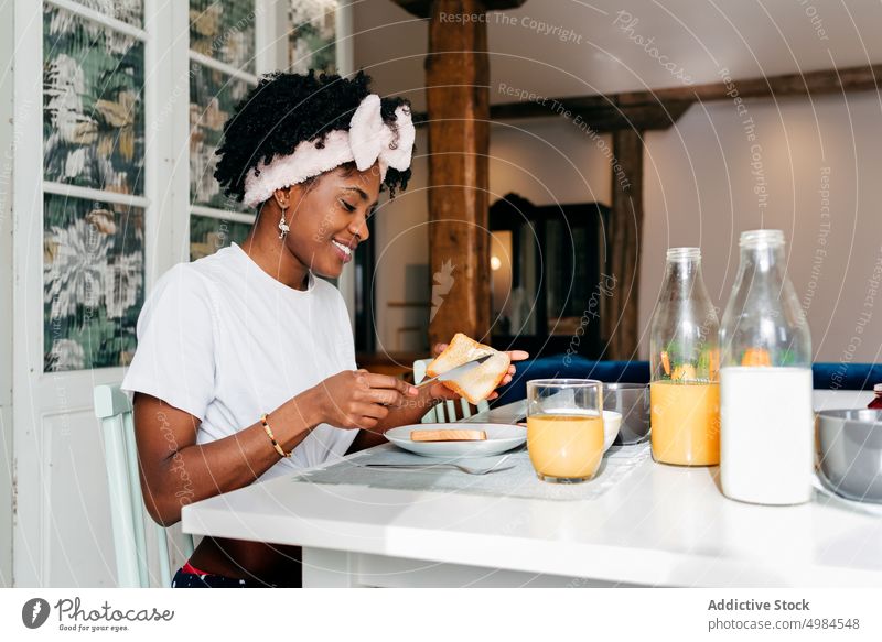 Black girl digging butter on a toast at breakfast woman home smile bread ethnic morning young female healthy cereal food lifestyle table meal happy cheerful