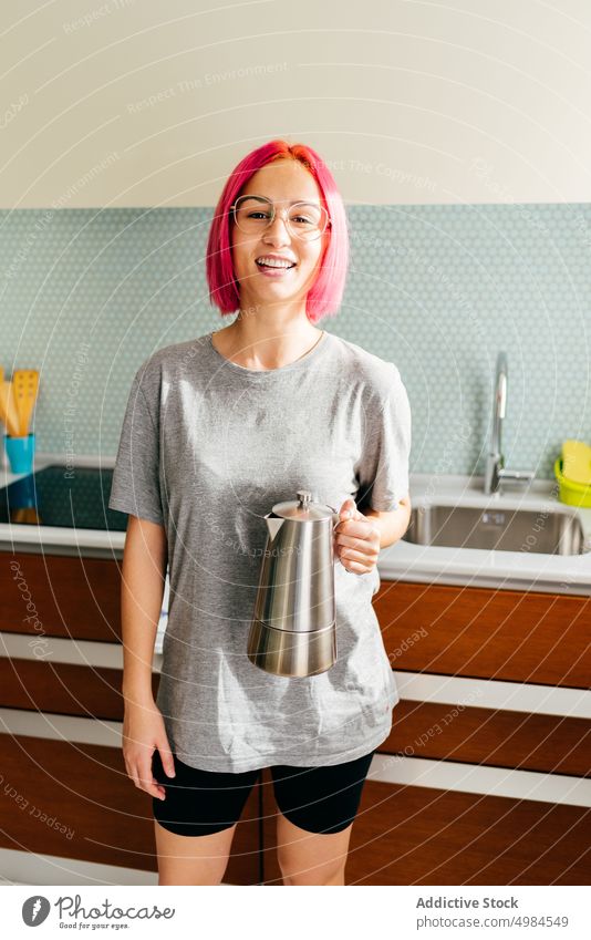 Happy young woman with coffeemaker kitchen morning breakfast smile prepare drink modern female dyed hair cheerful lifestyle beverage trendy pot brew energy lady