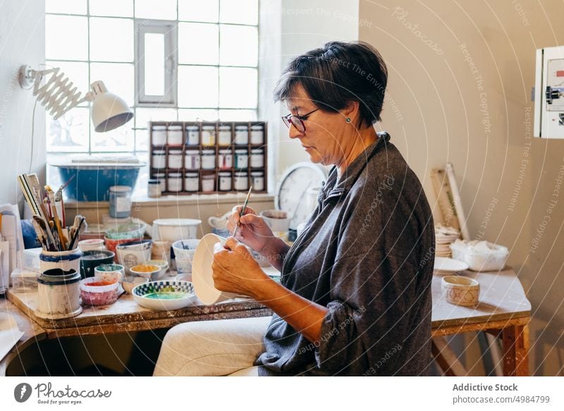 Skilled artisan woman painting pottery in workshop craftswoman ceramic handicraft create bowl handmade brush clay master skill process small business female