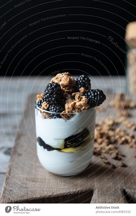Glass full of walnut granola with blueberries glass blueberry yogurt mix board wooden cutting chopping jar ripe pile fresh food delicious healthy natural diet
