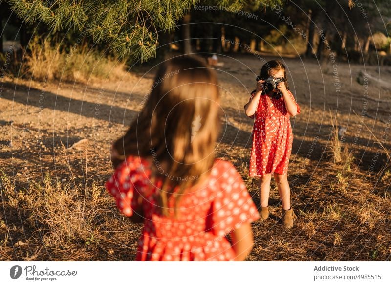 Girl taking photo of little sister in meadow girl friendship summer field nature camera photography beautiful technology adorable red child enjoyment device
