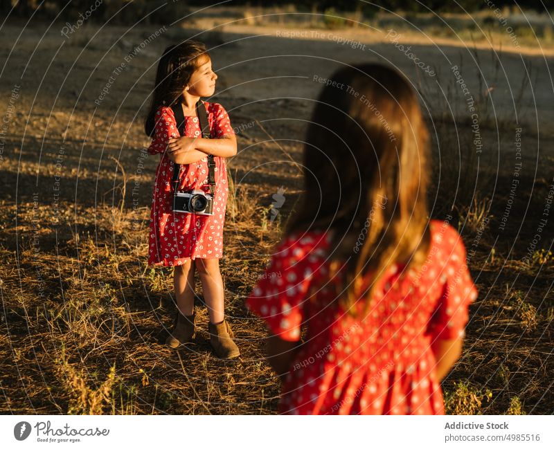 Girl taking photo of little sister in meadow girl friendship summer field nature camera photography beautiful technology adorable red child enjoyment device