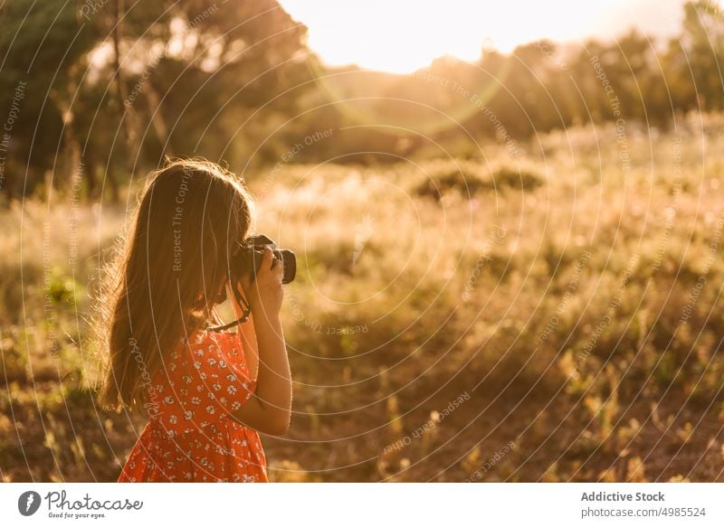 Little girl taking photo of landscape in sunny day summer field nature camera photography happy meadow beautiful adorable red child enjoyment device dress ears