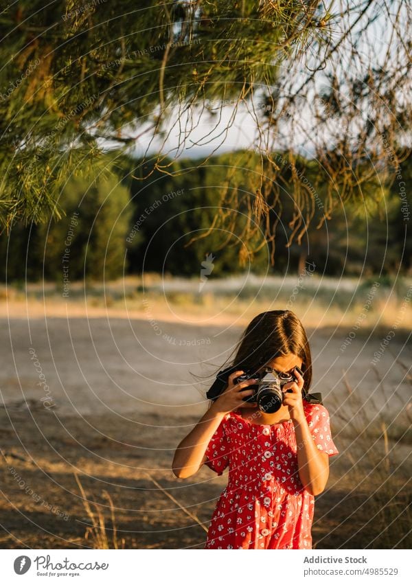 Little girl taking photo of landscape in sunny day summer field nature camera photography happy meadow beautiful adorable red child enjoyment device dress ears