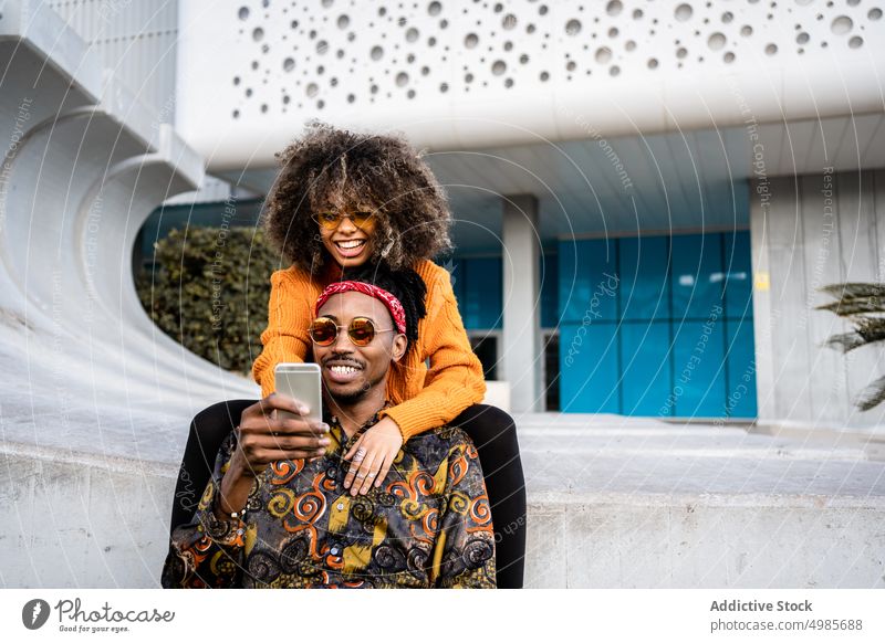 Laughing stylish ethnic couple taking selfie on bench trendy smartphone urban using share style black african american cool street style cheerful happy afro