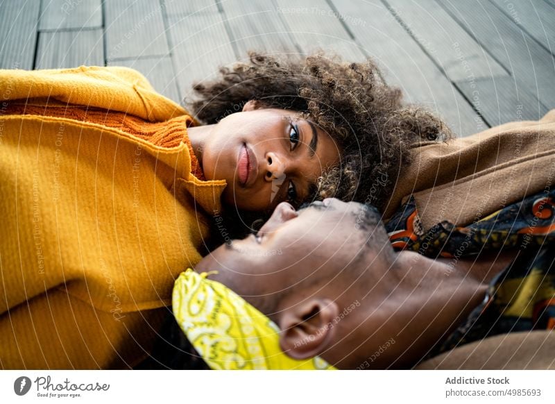Sensual black couple in colorful clothes lying ace to face love trendy face to face lying down fashion together autumn ethnic african american tender romantic