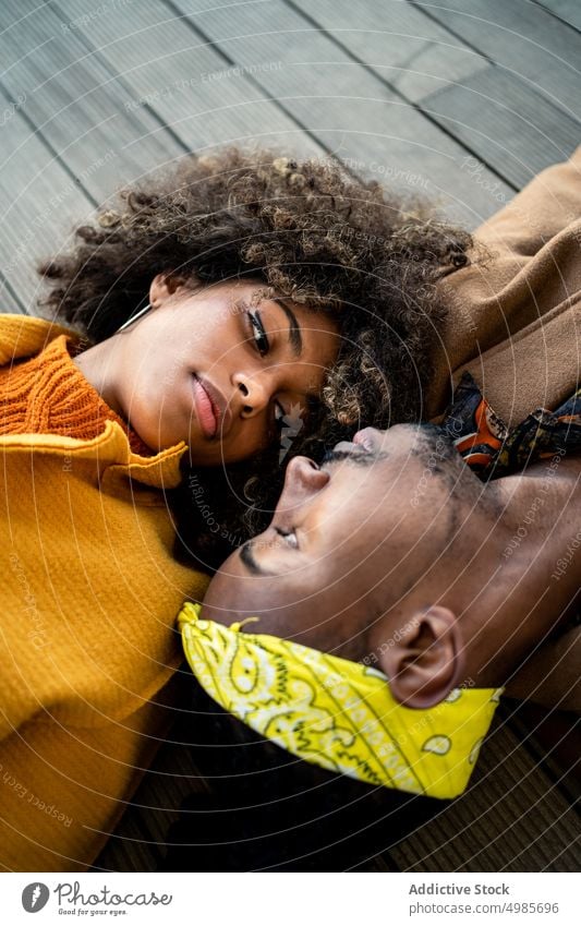 Sensual black couple in colorful clothes lying ace to face love trendy face to face lying down fashion together autumn ethnic african american tender romantic