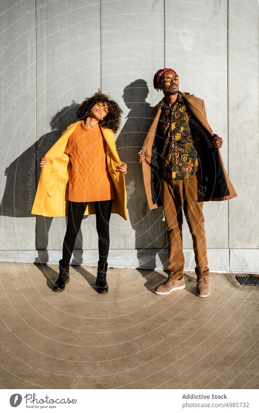 Trendy couple in stylish clothes standing on street woman fashion coat colorful street style together city trendy ethnic black african american afro exterior