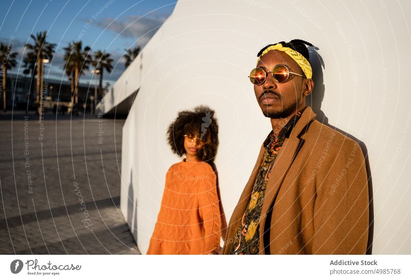 Modern black man and woman against white wall in sunset couple style city ethnic together street style cool african american contemporary sunlight sunglasses