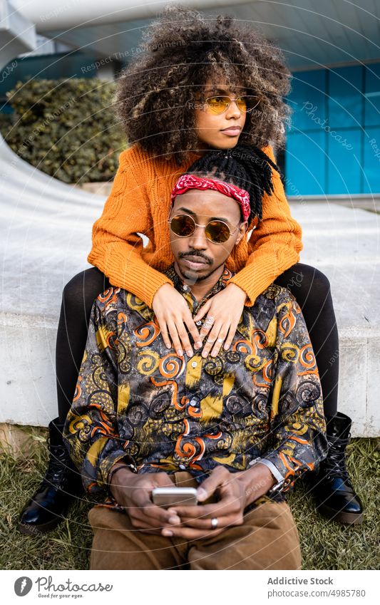 Laughing stylish ethnic couple taking selfie on bench trendy smartphone urban using share style black african american cool street style cheerful happy afro