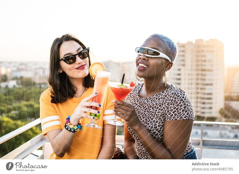Multiethnic couple of cool lesbian women drinking cocktails summer tropical cheers toasting lgbt refreshment girlfriend multiethnic multiracial diverse black