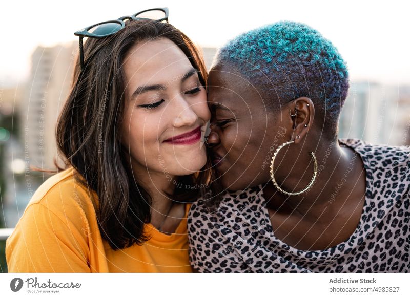 Multiracial lesbian couple sitting close together outdoors closeness relationship bonding love lgbt homosexual young multi ethnic multiracial asian female