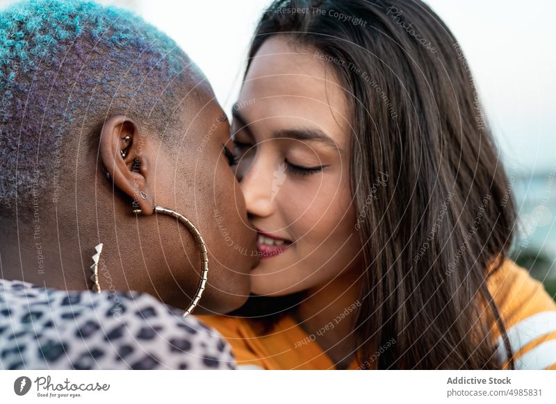 Multiracial lesbian couple sitting close together outdoors closeness relationship bonding love kiss kissing lgbt homosexual young multi ethnic multiracial asian