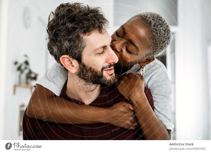 Tender multiethnic couple embracing at home love hug embrace cuddle relationship casual smile together romantic affection african american apartment black