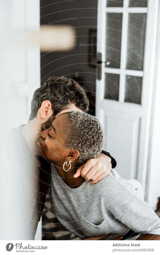 Carefree multiethnic lovers in embrace couple hug cuddle home relationship sit table kitchen modern casual together romantic affection african american black