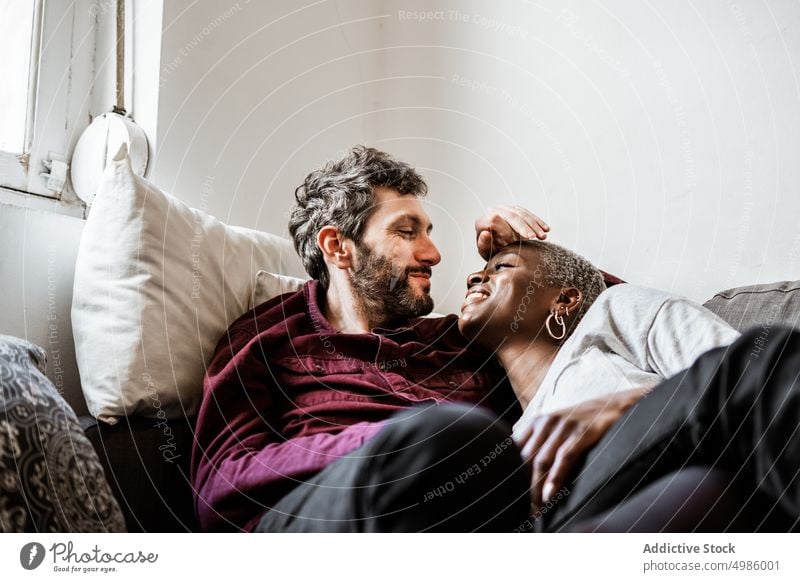 Young multiethnic couple resting on sofa cuddle couch asleep harmony calm home love relax living room bonding relationship hug leisure embrace together romantic