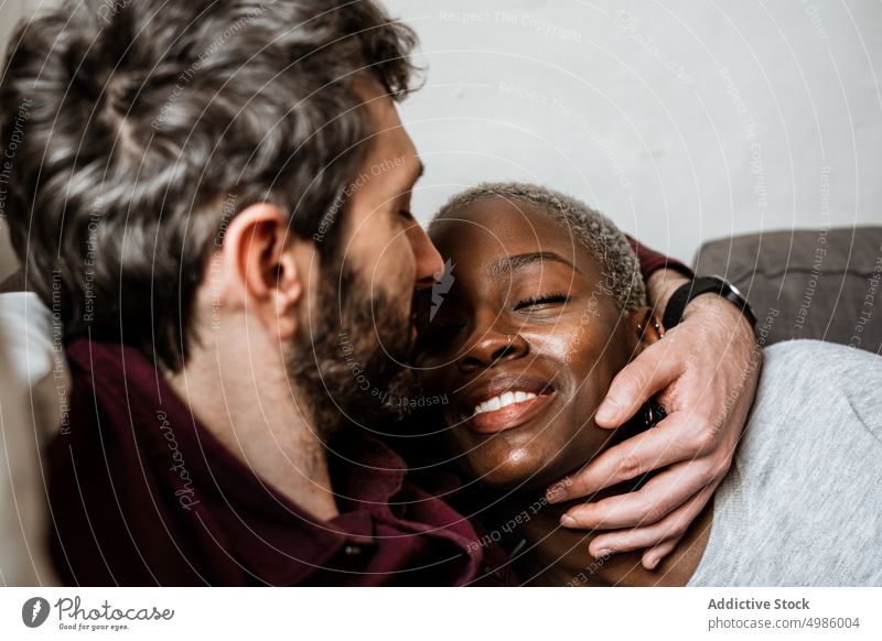 Young multiethnic couple resting on sofa cuddle couch asleep harmony calm home love relax living room bonding relationship hug leisure embrace together romantic