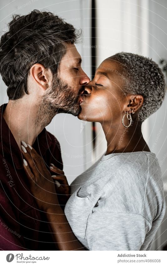 Happy couple cuddling in modern room love hug home embrace cuddle relationship smile laugh enjoy casual together romantic affection multiethnic african american