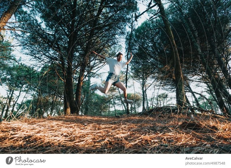 Young woman jumping spreading legs on the forest during a sunny day. Freedom and liberty concept person freedom joy happiness female happy achievement action