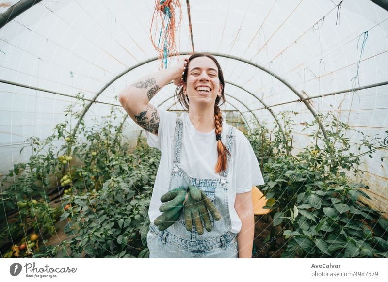 Woman standing in the middle of greenhouse,smiling happy with new job,working the farm while young person gardening growth horizontal lifestyles one person