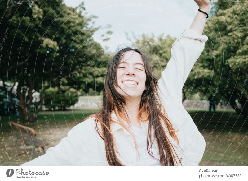 Young carefree woman with long hair on the park smiling and dancing. Freedom and liberty concept person freedom joy happiness fun happy portrait 20s arm