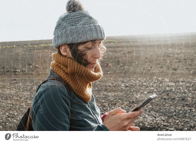 Young woman traveler checking writing on smart phone during sunset day at Iceland with copy space connection horizontal journey one person sharing vacations
