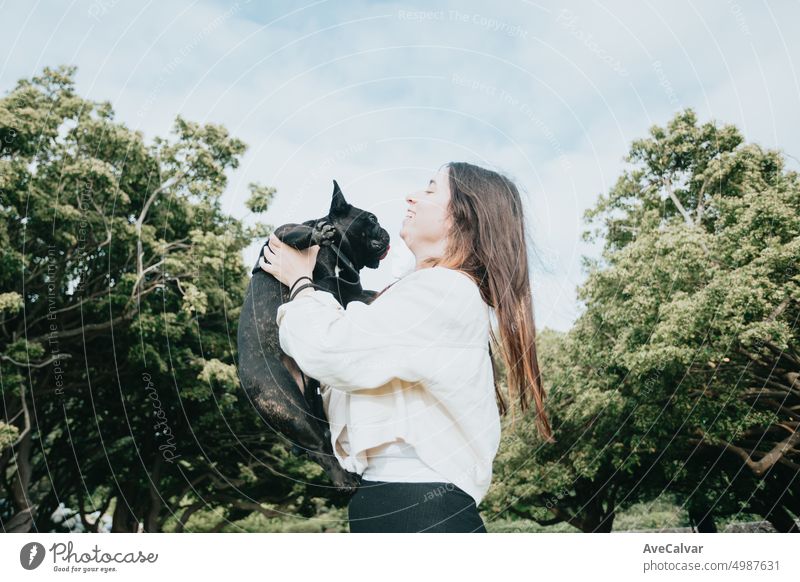 Young woman holding in arms french bulldog during a walk, dancing and playing with him. Adopt a dog dance emotion enjoy expression fashionable gorgeous indoor