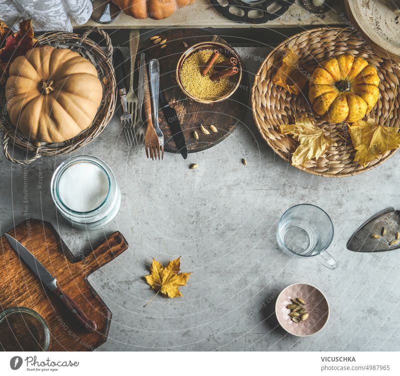 Autumn food background with pumpkins, cutting board and knife, various spices and kitchen utensils autumn top view orange color rustic cooking table group