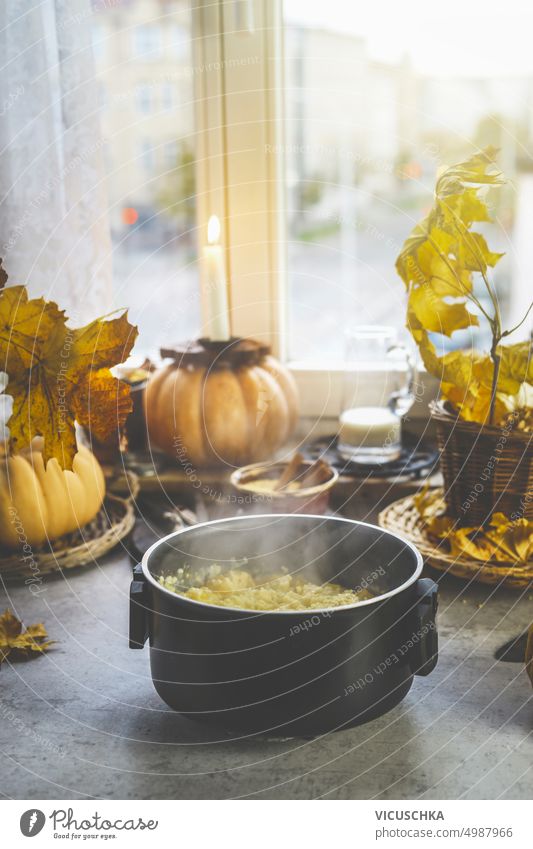 Steamed cooking pot with autumn comfort food on kitchen table with pumpkins at window steamed lifestyle candle delicious meal background tasty cozy hot vegan