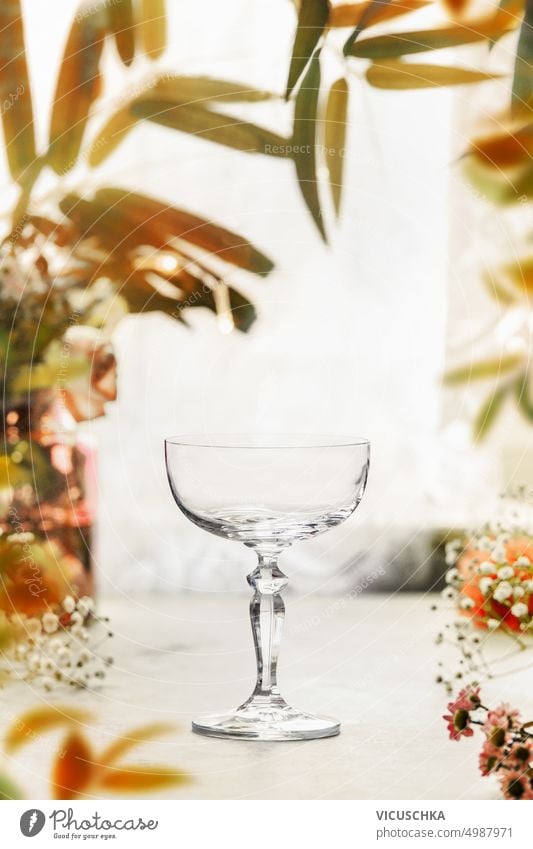Empty champagne cocktail glass on table with autumn leaves frame, front view empty champagne glass yellow elegant setting white beverage still life composition